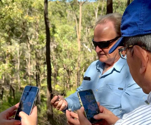 A group of people standing around each other holding cell phones.