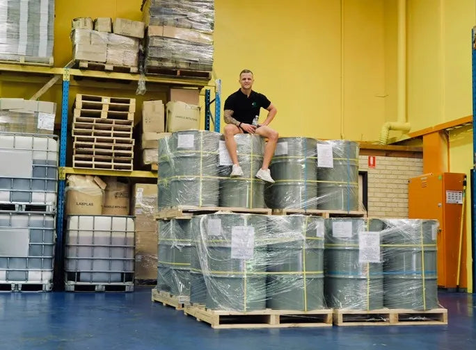 A man sitting on a pallet in a warehouse.